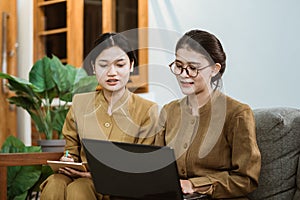 state official and assistant in civil servant uniforms sit together on sofa while working online using laptop