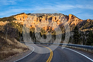 State Road 14 leads toward cliff of orange and red rock towers and hoodoos