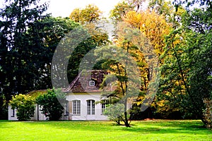 Stately garden with meadow and old trees in autumn colors and small garden shed