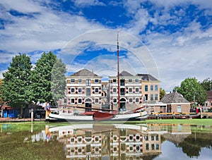 Stately monumental mansion with moored boat mirrored in a canal, Gouda, Netherlands