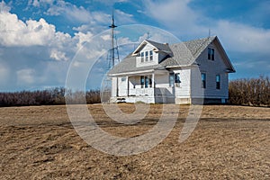 A stately old, abandoned home on the Saskatchewan prairieswith a crib in the foreground