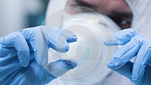 Static shot of researcher in white coverall analyzing a sample