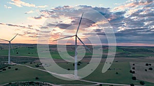 Static video from a drone of a wind turbine operating silhouetted against the sunset from behind. Renewable energy concept