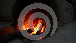 Static view of a large black pot over glowing embers in a rural setting. Indian village life concept
