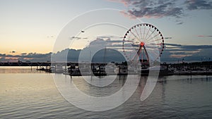 Stationary Capital Wheel at National Harbor at sunset with plane coming in to land