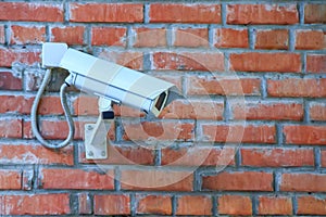 Stationary outdoor video camera of a security video surveillance system on a brick wall