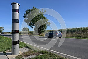 Stationary speed limit enforcement beside a road and a blurred passing car, traffic monitoring with light radar and camera to