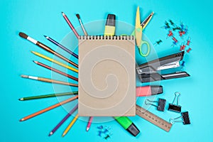 Stationery colorful writing tools accessories pens pencils, Kraft paper isolated on blue background. Back to school. Office suppli