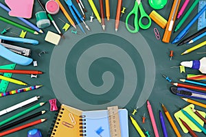 Stationery lies in a circle on a green background. Kids stationery on school board.