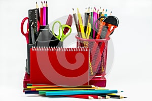 Stationery in two glasses, a red notebook, pencils isolated on a white background