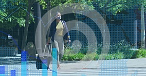 Statistical data processing against woman wearing face mask with trolley bag crossing the street