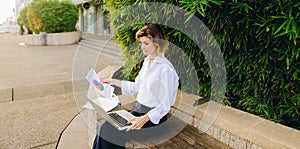 Statistician working outside with laptop and color diagrams.