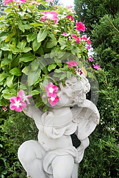 Statue of an angel holding a rose sitting on a tombstone in a ce