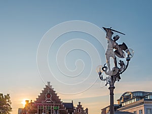 Statue of Archangel Saint Michael slaying a dragon next to promenade of river Lys in Ghent, Belgium and at dusk
