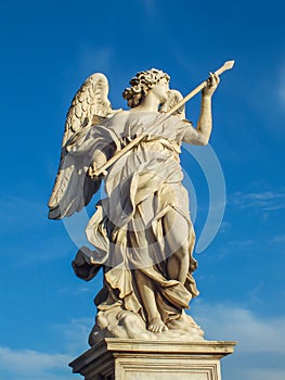 Statue of a holy angel with wings holding a war spear at the Saint Angel bridge on sky, Rome, Italy.