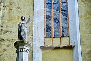 Statue of Bishop Georg Paul Binder next to a window with round glass pattern, near the entrance in Biertan fortified church.