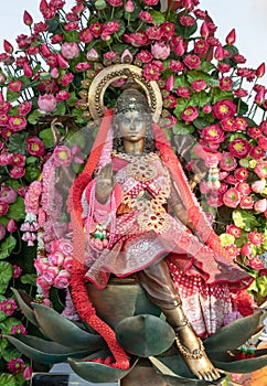 Statue of Brass Hindu Goddess Lakshmi (Maha Laxshmi) is decorated with flowers garland and Bouquet of Pink Lotus