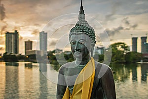 Statue of Buddha in a peacefull pose, in front of a cityscape photo