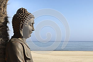 Statue of Buddha sitting on the beach.