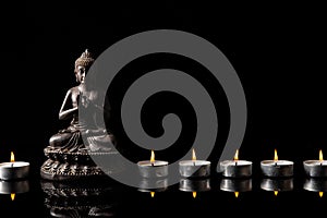 Statue of Buddha sitting in meditation, .candle line With black copy space . Zen and meditation concept