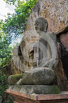 Statue of Buddha sitting in meditative calm, in the lotus position, made of concrete