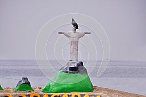 Statue of Christ the Redeemer made of beach sand. With a pigeon on top of the sand statue. photo