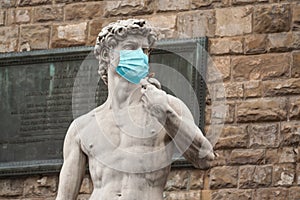 The Statue Of David in the Piazza della Signoria In Italy Wearing Blue Protective Medical Face Mask photo