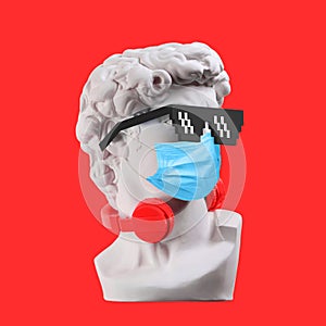 Statue. Earphone on a red background. Gypsum statue of David`s head. Creative. Plaster statue of David`s head in sunglasses and