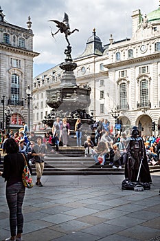 Statue of Eros or Anteros with Darth Vader street performer in Picadilly Circus, London, UK