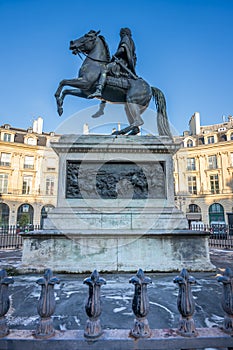 Statue of the French King Louis XIV (14th) in the center of Victories Place in Paris under a pure cold blue sky