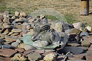 Statue of a frog on a water lily. A statue on pebbles.