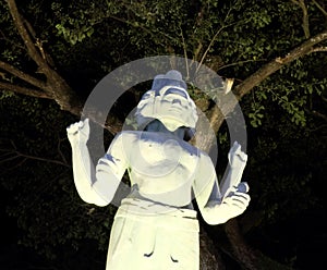 The statue of a Hindu deity with four hands and several faces, night lighting, Asian culture