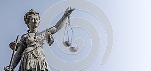 Statue a judge woman with scales and sword at smooth blue background in Frankfurt, Germany, details, closeup