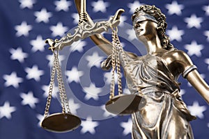 The statue of justice Themis or Justitia, the blindfolded goddess of justice against the flag of the United States of America