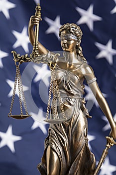 The statue of justice Themis or Justitia, the blindfolded goddess of justice against the flag of the United States of America