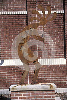 Statue of Kokopelli, Quetzal God with brick wall in background