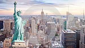 The Statue of Liberty with aerial view of Manhattan skyline background, skyscraper in New York City at sunset in evening