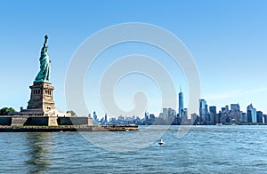 Statue of Liberty with Manhattan skyline in New York. Panorama view to the downtown of NYC. Tourists sightseeing in Liberty Island