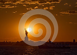 The Statue of Liberty at sunset with the sun just above Liberty`s shoulder