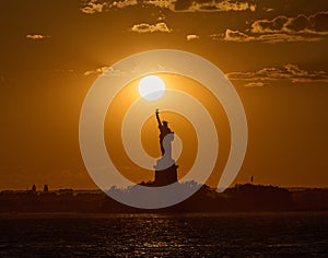 The Statue of Liberty at sunset with the sun just above the torch
