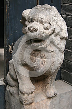 statue of a lion at the entrance of an old house in pingyao (china)