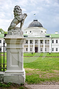 Statue of lion holding a shield in its paws. Regal lion leaning on empty heraldic shield near the castle entrance. The palace and