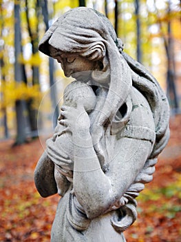 Statue of Madonna and child in autumn forest