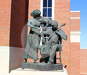 Statue of a man and woman playing violins at The Gertrude Castellow Ford Center on the campus of Ole Miss