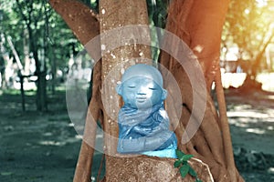 The statue of a monk meditating with a smile under a big tree