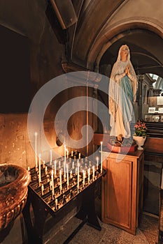 Statue mother virgin mary praying and candlelight altar in christian chruch