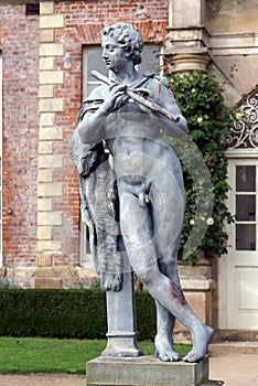 Statue of a musician playing flute, Powis castle garden, UK