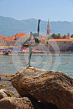 Statue of Naked Dancing Girl on a Rock with Budva Old Town in the Background