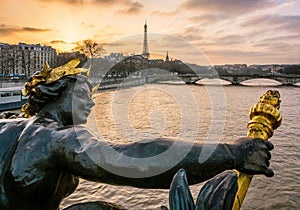 The statue of a nymph ornamenting the Pont Alexandre III in Paris, with the Eiffel tower in the background at sunset