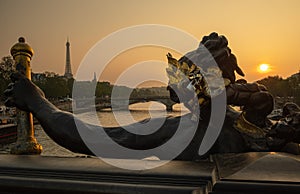 Statue of Nymphs with locks on Alexandre III bridge with Eiffel Tower in the background at sunset time in Paris